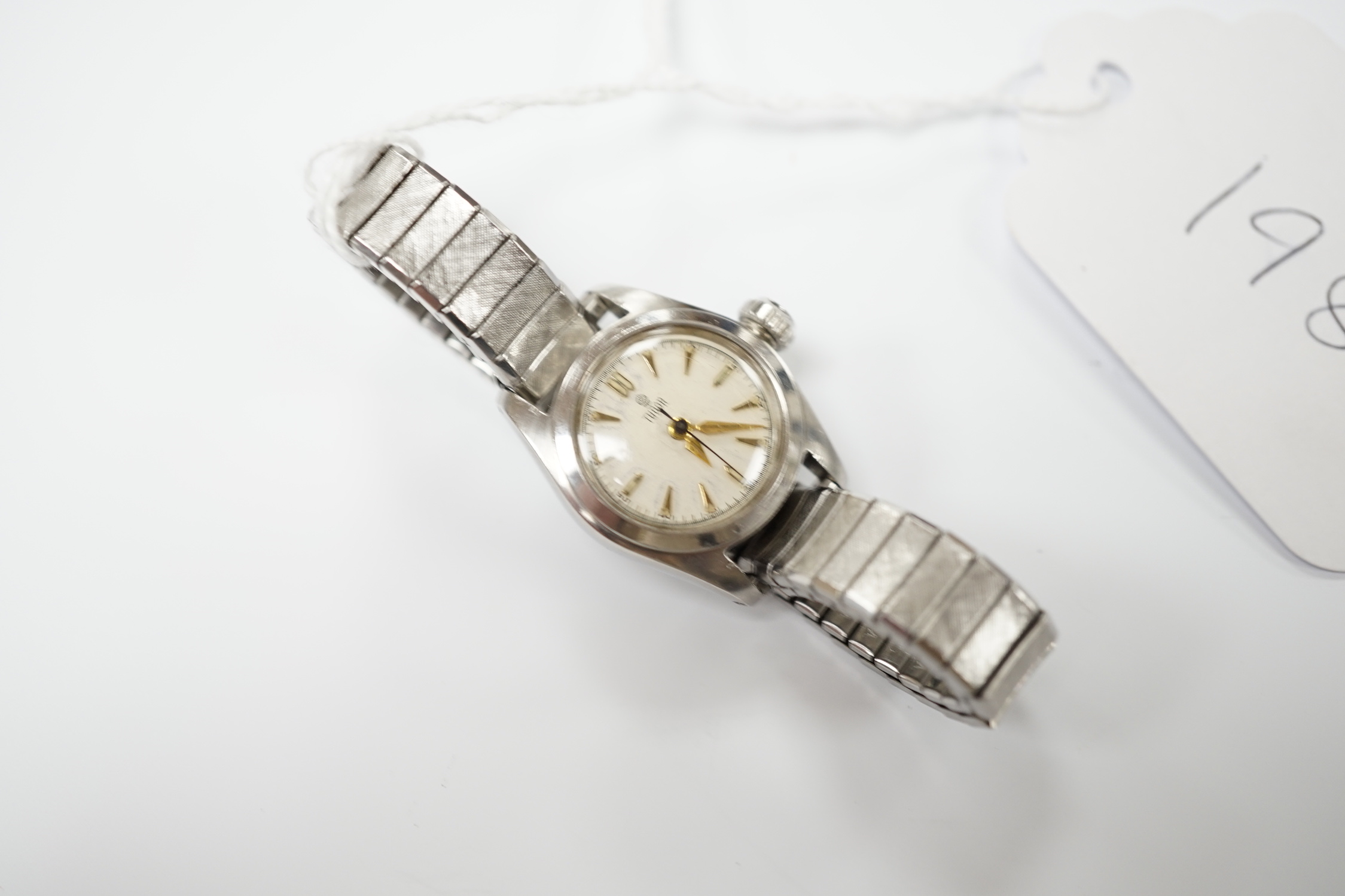A lady's stainless steel Tudor manual wind wrist watch, with baton numerals, on an associated flexible bracelet.